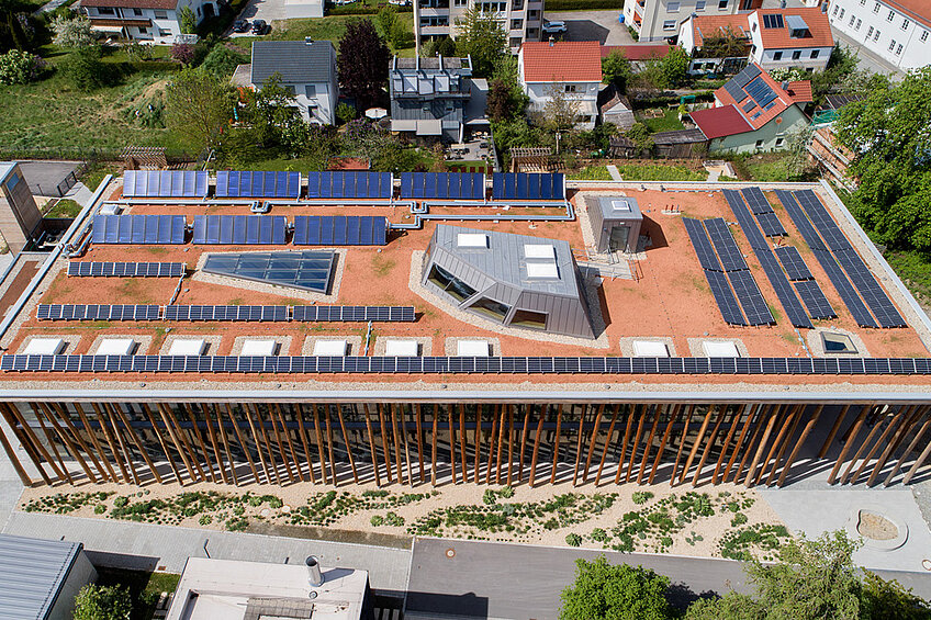Luftaufnahme des NAWAREUM-Baus mit sichtbarer Südfassade sowie Flachdach mit Photovoltaik und Solarthermieanlage.